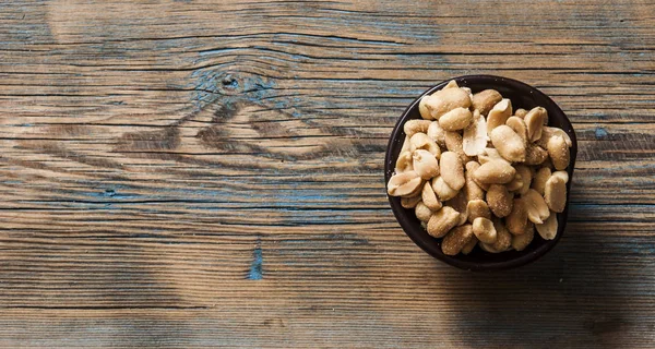 Roasted, salted peanuts are placed on a wooden background — Stock Photo, Image