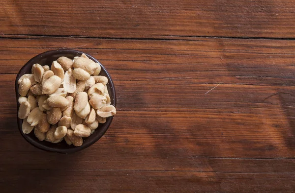 Roasted, salted peanuts are placed on a wooden background — Stock Photo, Image