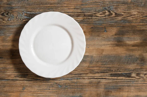 Пустая тарелка на старом деревянном столе — стоковое фото