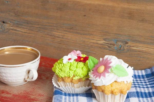 Bloem lente cupcake met warme koffie cup op houten tafel — Stockfoto