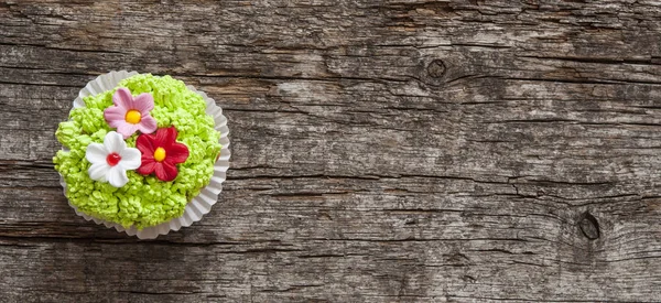 Gâteaux décorés avec des fleurs pour le printemps fond en bois — Photo