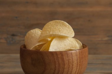 Ahşap kase gevrek patates cipsi. Tuzlu patates cipsi. 