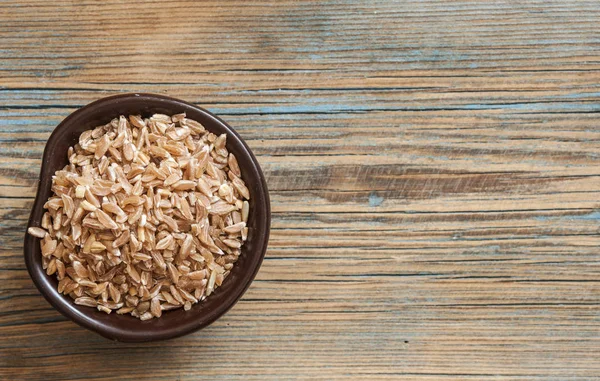 Bowl with Spelt (close-up shot) on wooden background — Stock Photo, Image