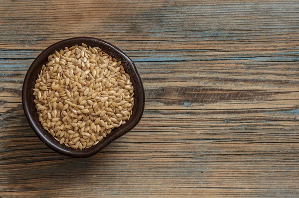 Flax seeds in a bowl with a spoon on a wood vintage background. — Stock Photo, Image