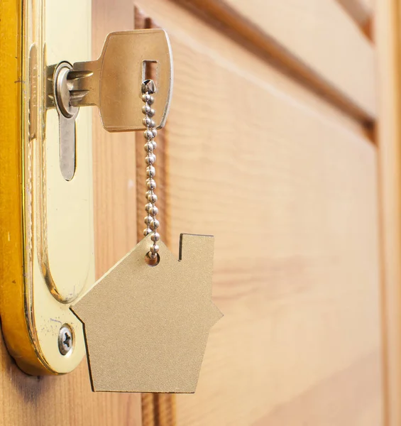 房子买一栋房子的钥匙状银匙扣在一扇门的锁 — 图库照片