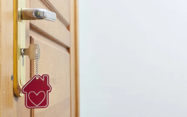 Hus nyckel på ett hus formade silver keyring i låset i en dörr — Stockfoto