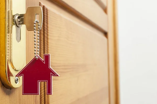 Hus nyckel på ett hus formade silver keyring i låset i en dörr — Stockfoto