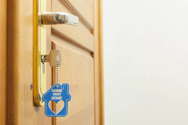 House key on a house shaped silver keyring in the lock of a door — Stock Photo, Image