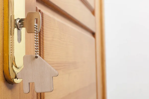 Llave de la casa en un llavero de plata en forma de casa en la cerradura de una puerta — Foto de Stock