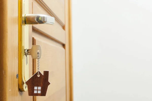 Hausschlüssel an einem hausförmigen silbernen Schlüsselanhänger im Türschloss — Stockfoto