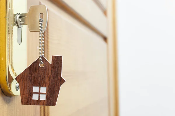 Llave de la casa en un llavero de plata en forma de casa en la cerradura de una puerta — Foto de Stock