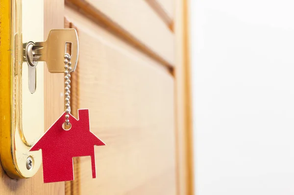 Ház kulcsát egy ház alakú ezüst kulcstartó a bezár ajtó — Stock Fotó