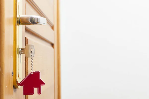 Chiave di casa su un portachiavi in argento a forma di casa nella serratura di una porta — Foto Stock