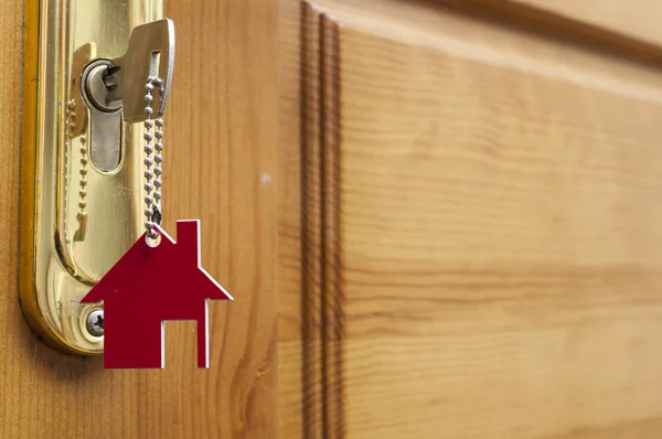 House key on a house shaped silver keyring in the lock of a door — Stock Photo, Image