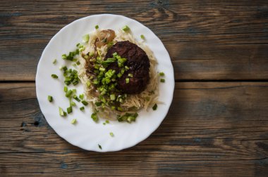 ahşap bir arka plan üzerinde bir tabak üzerinde makarna ile pirzola 