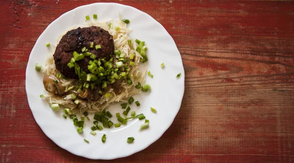 Ahşap bir arka plan üzerinde bir tabak üzerinde makarna ile pirzola — Stok fotoğraf