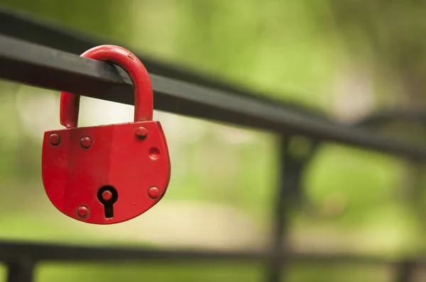 Red padlock in the shape of a heart, on a metal pipe — Stock Photo, Image