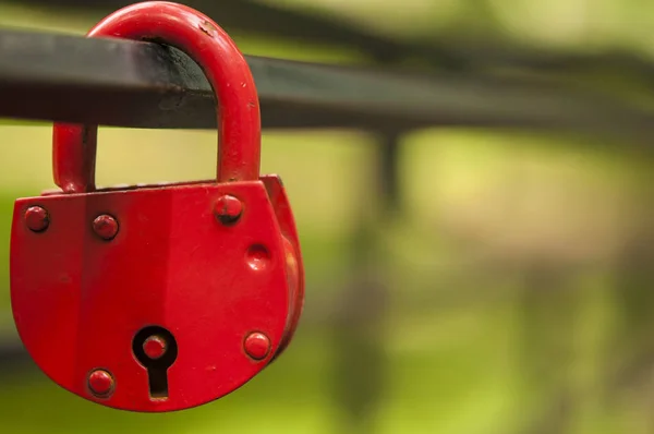 Red padlock in the shape of a heart, on a metal pipe — Stock Photo, Image