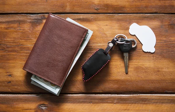 Leather wallet and car key on wood table with dollar bills — Stock Photo, Image