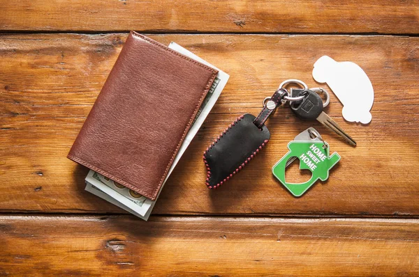 Шкіряний гаманець і ключ від автомобіля на дерев'яному столі з доларовими купюрами — стокове фото