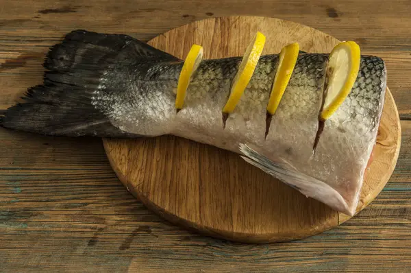 Cola de salmón con limón y sal marina sobre mesa de madera —  Fotos de Stock