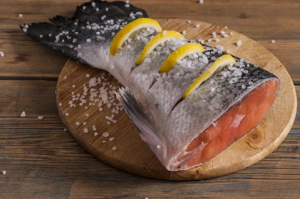 Cola de salmón con limón y sal marina sobre mesa de madera —  Fotos de Stock