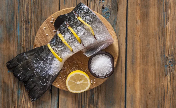 Cola de salmón con limón y sal marina sobre mesa de madera —  Fotos de Stock