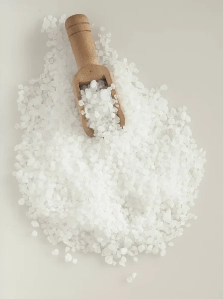 Nagy tengeri só egy fakanállal, szürke háttér. Az élelmiszer-összetevőke — Stock Fotó