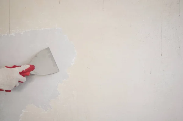 Mão com uma espátula limpa a parede de papel de parede — Fotografia de Stock