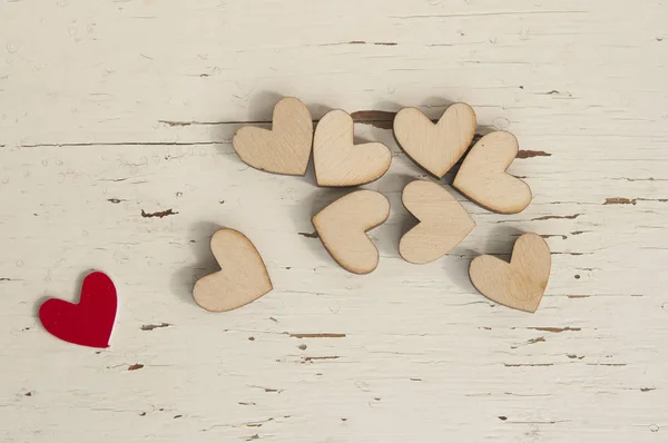 Red heart and many wooden hearts on white wooden background. — Stock Photo, Image