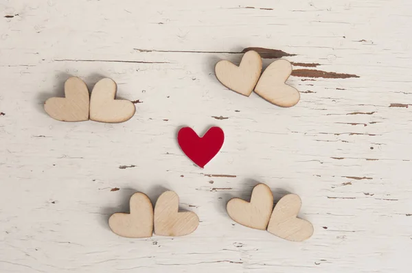 Rudé srdce a mnoho dřevěných srdcí na bílém dřevěném pozadí. — Stock fotografie