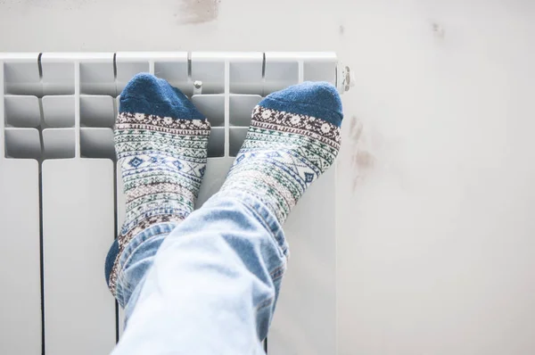 Homme jambes chauffantes sur radiateur de chauffage près du mur blanc — Photo