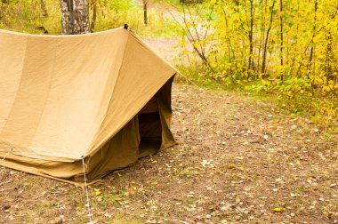 Eski, beyazlatılmış, sarı Sovyet çadırı çimlerin üzerinde duruyor. Yakın plan.