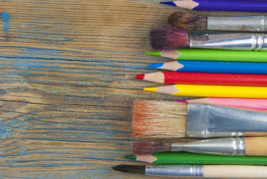 Birkaç renkli kalem ve fırça birlikte ahşap arka planda yakınlaşır.