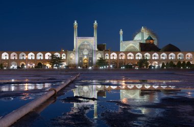 İsfahan 'ın Naqshe Cihan Meydanı' ndaki bir su birikintisine yansıyan İmam Camii 'ni gece karanlığında mavi gökyüzüne karşı aydınlattı..