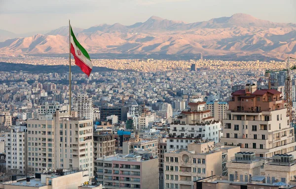 Mávání Íránskou Vlajkou Nad Obzorem Teheránu Při Západu Slunce — Stock fotografie