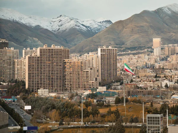 德黑兰的天际线和在雪地上飘扬的伊朗国旗覆盖了阿尔伯尔兹山 并带来了温室效应 — 图库照片