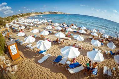Paphos, Kıbrıs - 20 Ağustos 2017: Satır beach Lounge ve güneş şemsiyesi Peyia köyü çevre Coral Bay beach üzerinde.