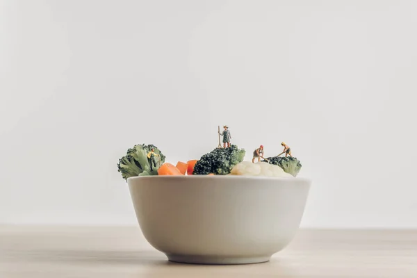 Повна чаша свіжого салату зелена зібрана мініатюрними фермерами — стокове фото