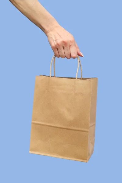 Hand Holding Paper Bag Handles Blue Background — Stock Photo, Image