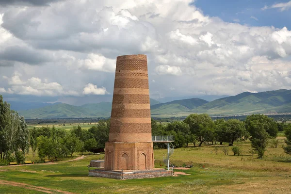 Burana tower is a historical tourist attraction in Kyrgyzstan . Ruins of an ancient city on the background of picturesque mountains and sky with clouds.
