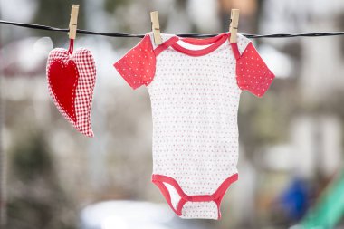 Bebek giysileri ve clothesline üzerinde asılı bir kırmızı kalp