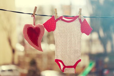 Bebek giysileri ve clothesline üzerinde asılı bir kırmızı kalp