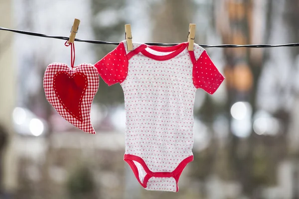 赤ちゃんの服や物干しに掛かっている赤いハート — ストック写真