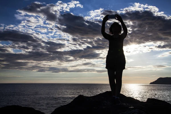Silhoette 年轻的旅行妇女在日落时拍照与智能手机 — 图库照片