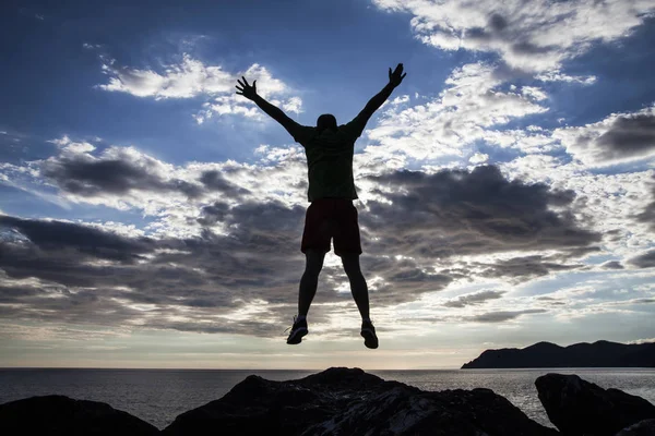 在日落的悬崖上跳跃的人的剪影 自由概念 — 图库照片