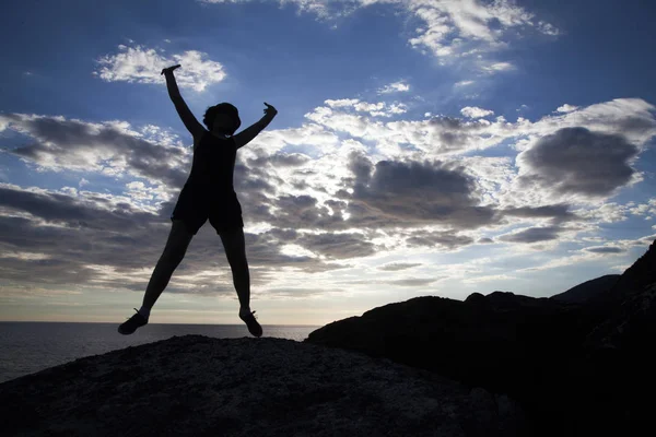在日落的悬崖上跳跃的女人的剪影 自由概念 — 图库照片