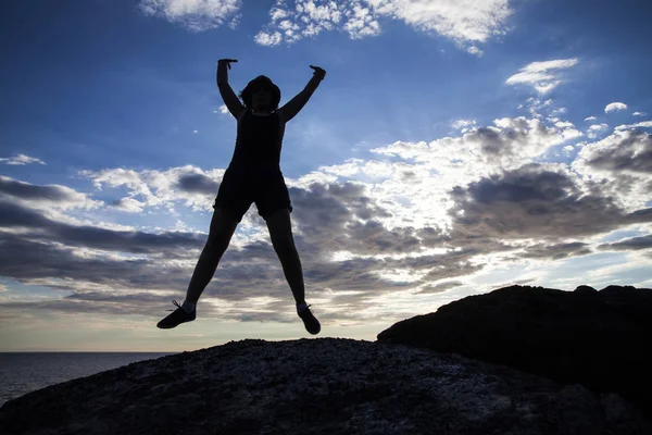 在日落的悬崖上跳跃的女人的剪影 自由概念 — 图库照片