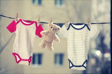 Clothesline üzerinde asılı bebek giysileri ve bir oyuncak ayı