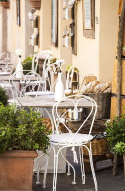 Beyaz sandalye ve beyaz çiçekleri ile İtalyan bir sokakta rahat Teras